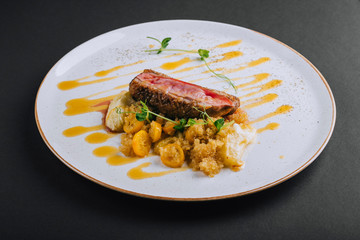 Duck breast fillet with quinoa garnish with young pea sprouts on a black background