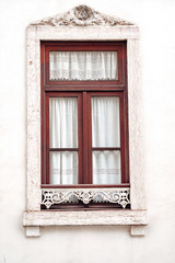 Fototapeta premium Ornate window with white moulding and lace curtains, typical of the architecture of Lisbon, Portugal