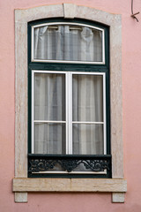 Fototapeta na wymiar Pretty pink window in portrait orientation in Lisbon, Portugal, typical of the architecture of the area