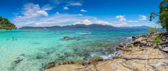 Fototapeta premium sea view panorama of arch rocks and tourists in blue-green sea with blue sky background, Ko Rokroy, Tarutao National Park, Satun, southern of Thailand.