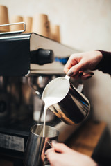 The girl's hands close-up pour whipped milk into the cup.