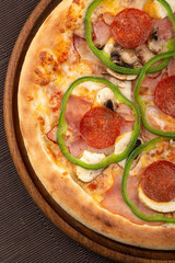 Delicious fresh pizza on table.  Delicious pizza. Large meat pizza with bacon, sausage, salami, pepperoni and olives. Homemade delicious italian pizza on wooden table for dinner. Italian cuisine.