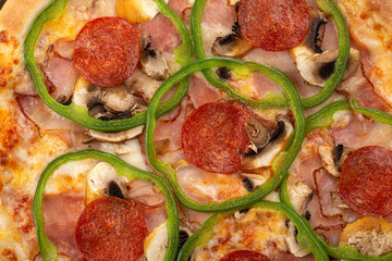 Delicious fresh pizza on table.  Delicious pizza. Large meat pizza with bacon, sausage, salami, pepperoni and olives. Homemade delicious italian pizza on wooden table for dinner. Italian cuisine.