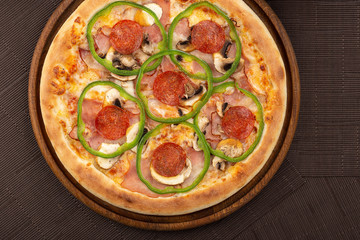 Delicious fresh pizza on table.  Delicious pizza. Large meat pizza with bacon, sausage, salami, pepperoni and olives. Homemade delicious italian pizza on wooden table for dinner. Italian cuisine.