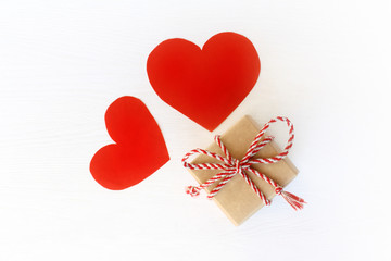 gift box with bow and a pair of red hearts top view. surprise for lovers