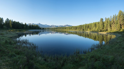 Fototapeta na wymiar Morning fog on a mountain lake. Reflections in the water, panorama. Dawn in the Altai Mountains.