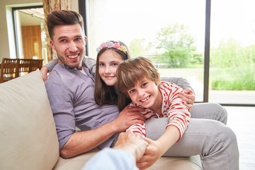 Fototapeta premium Glücklicher Vater mit zwei Kindern auf dem Sofa