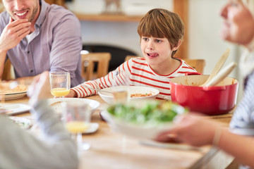 Hungriger Junge am Esstisch mit der Familie