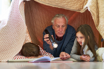 Großvater liest Enkel Kindern aus einem Buch vor