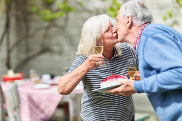 Paar Senioren küsst sich auf einer Gartenparty