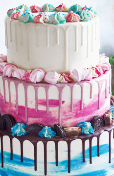 Three-tiered colored cake with colored smudges of chocolate on a light background. Picture for a menu or a confectionery catalog, the wedding cake