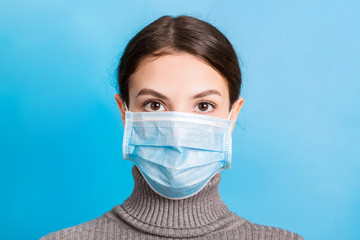 Portrait of young woman wearing medical mask at blue background. Protect your health. Coronavirus...