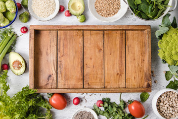 An assortment of seasonal vegetables and whole grains placed around over a  white surface and an...