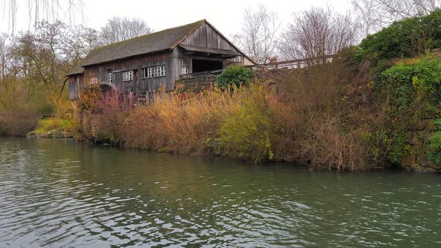 Molino de agua antiguo de madera girando sus aspas junto a r&iacute;o de oto&ntilde;o