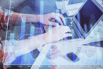 Double exposure of stock graph with businessman typing on computer in office on background. Concept of hard work.