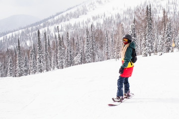 Fototapeta na wymiar Woman snowboarder rides a snowboard on a snowy slope.