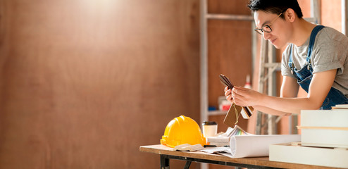 smart attractive handy glasses asian male craftman or interior designer focus wood working at site constrution home interior design renovation and improvement concept