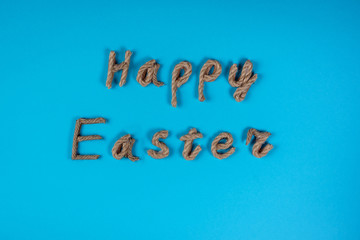 Happy Easter lettering made of rope on the blue background. Celebrating Easter, greeting or invitation card. Sprigtime.
