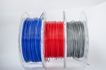 Plastic for 3D printing. Red, silver and blue plastic filament, ABS/PLA coil for 3d printer on white background, isolated