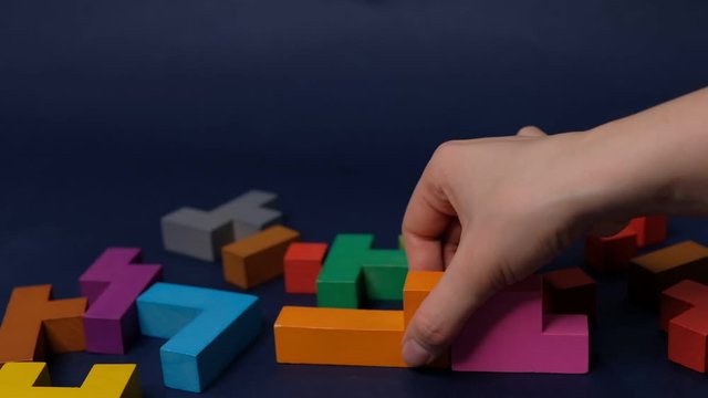 Closeup Slow motion. Hand holding piece of wooden block puzzle. wood cube stacking. Concept of complex and smart logical thinking. on a black background