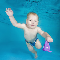 Little boy play with toy underwater in a swimming pool