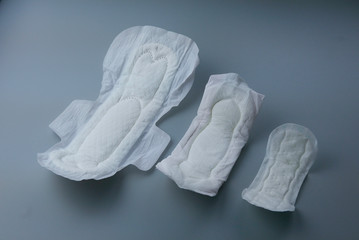 Side view of women sanitary pad in various size on grey background.