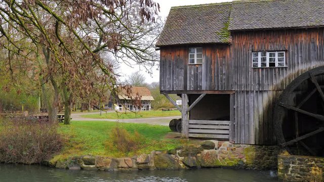 Viejo Molino de agua de madera girando sis aspas con arroyo en un campo oto&ntilde;al