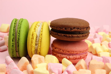Colored macaroons or macarons, marshmallow hearts on a pink background