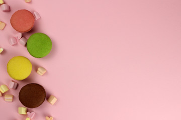 Colored macaroons or macarons on a pink background, copy space for your text