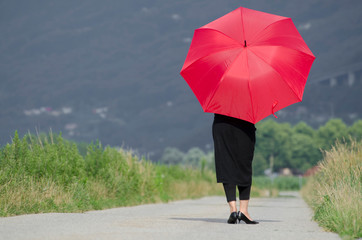 Woman Standing on an Empty Road and Waiting with a Red Umbrella.