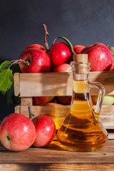 Homemade fruit canning, diet healthy food and drink. Apple cider vinegar, juice, salad dressing from a crop of ripe red garden fruits in a glass jug on a wooden rustic background