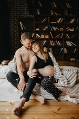 Happy man touching belly of smiling pregnant woman
