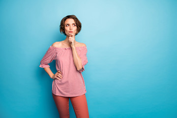 Photo of attractive lady look side empty space deep thinking hold finger on chin have doubts wear casual white red open shoulders blouse trousers isolated blue color background