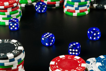 Dice and chips on black table close up