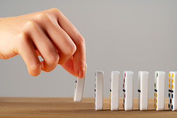 Woman hand toppling dominoes. Chain reaction business concept