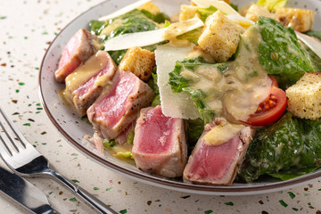 Delicious fresh salad. Caesar salad. Caesar salad with fresh lettuce, parmesan, fried croutons, tuna. Restaurant food, close up. Meat salad. Close up view.