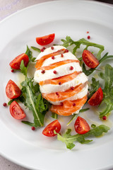 Delicious fresh salad. Salad with salmon, mozzarella cheese, cherry tomatoes, arugula, olive oil. Fresh salmon salad with mozzarella and vegetables. Close up view on Salad. Healthy, diet tasty summer 
