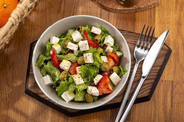 Delicious fresh salad. Greek salad with feta cheese, organic olives, juicy tomatoes, red pepper, red onion, cucumber and lettuce. Greek salad with fresh vegetables. Close up view on Salad. Healthy, di