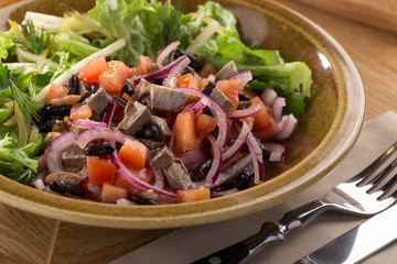 Delicious fresh salad. Veal salad with lettuce, apple, pear and tomato on wooden background. Restaurant food, close up. Meat salad. Close up view on Salad with warm baked veal, parmesan, cherry, lettu