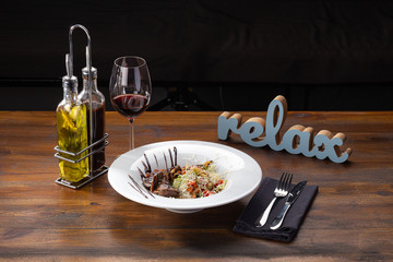 Delicious fresh salad. Warm salad with veal, peppers, lettuce on wooden background. Restaurant food, close up. Meat salad. Close up view on Salad with warm baked veal.