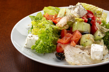 Delicious fresh salad. Greek salad with feta cheese, organic olives, juicy tomatoes, red pepper, red onion, cucumber and lettuce. Greek salad with fresh vegetables. Close up view on Salad. Healthy, di