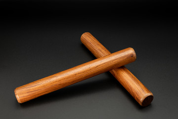 A pair of wooden claves lying on a black underground