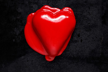 Heart-shaped cake covered with red icing on a black background, top view. Valentine's impression