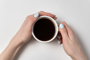 Cup of strong tea in hand on a white background. Neat manicure and a cup of coffee.