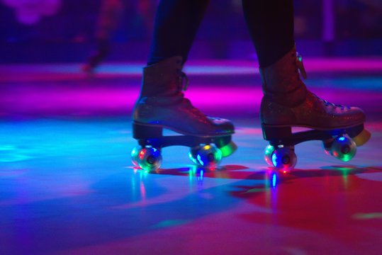 Low Section Of Person Roller Skating On Floor In Illuminated Rink
