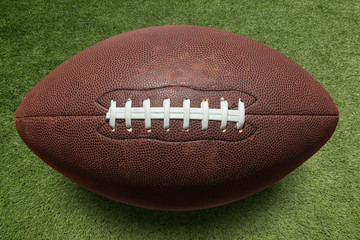 photo american football ball on grass stadium background.
