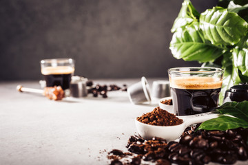 Background with glass cup of coffee, coffee beans and leafs. Beverage cafe shop concept with copy space. Toned photo