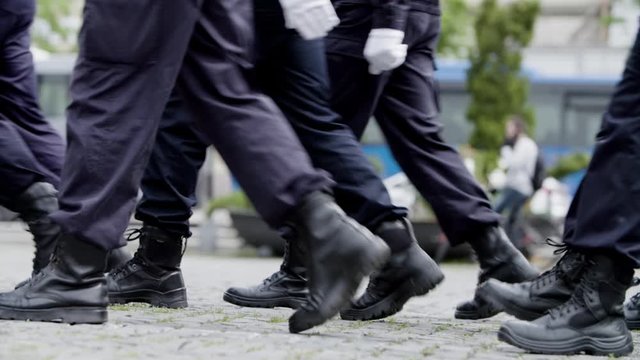 Slow motion close up of police men's feet marching through the city