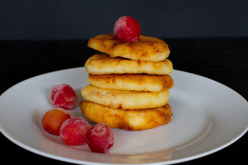 plate with pancakes and berries on a black background. the concept of a delicious Breakfast and menu. space for text. plate with homemade pancakes and cheesecakes.