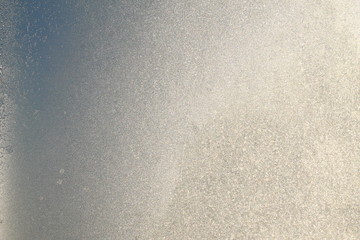 Blue window glass covered hoarfrost ice pattern texture with water drops. Cold nature winter background